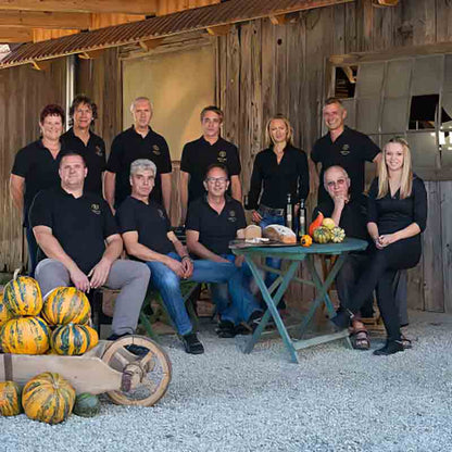 Team der Ölmühle Hartlieb vor rustikaler Holzhütte mit Kürbissen an der Seite.