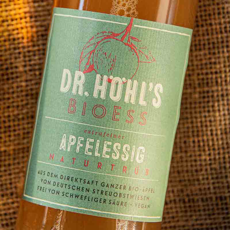 Dr. Höhl's Bioess Apfelessig Flasche auf Jute-Hintergrund.