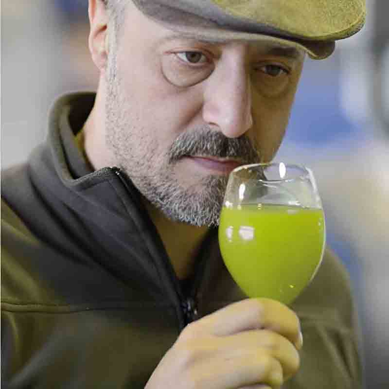 Mann riecht an Olivenölglas.