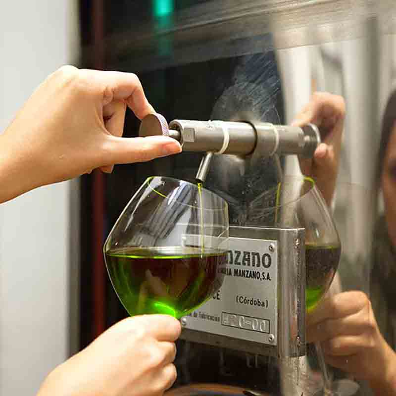 Person füllt Glas mit Olivenöl aus Spender.