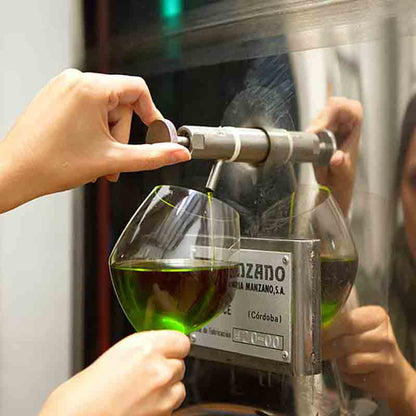 Person füllt Glas mit Olivenöl aus Spender.