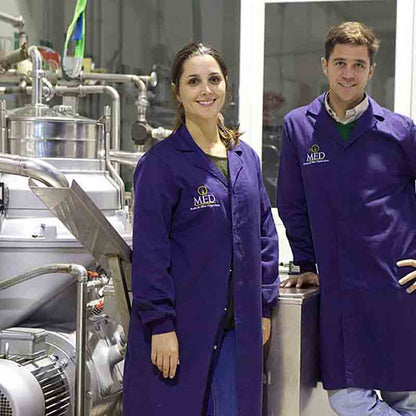 Paola und Juande, Inhaber der Ölmühle, stehen neben der Produktionsanlage in der Mühle.