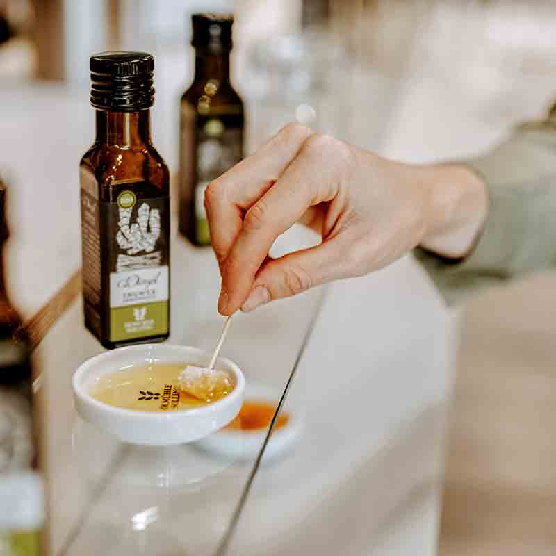 Hand taucht Brot in Olivenöl von Ölmühle Solling.