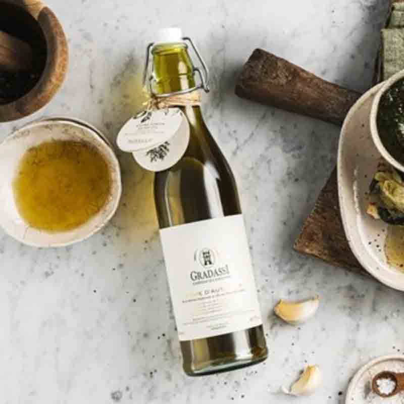 Flasche Olivenöl, Schalen, Knoblauch auf Marmortisch, Marke Gradassi.