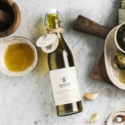 Flasche Olivenöl, Schalen, Knoblauch auf Marmortisch, Marke Gradassi.