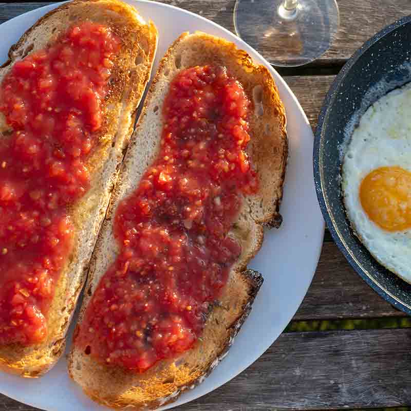 Toast mit Tomaten, Spiegelei, Weinglas auf Holztisch.