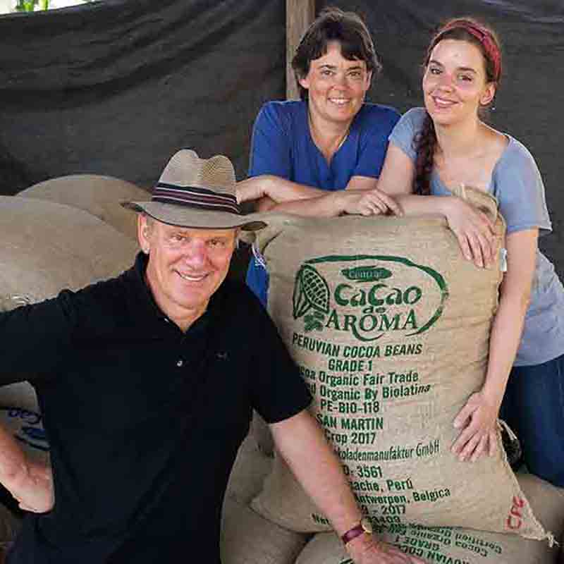 Drei Personen mit Kakaosäcken.