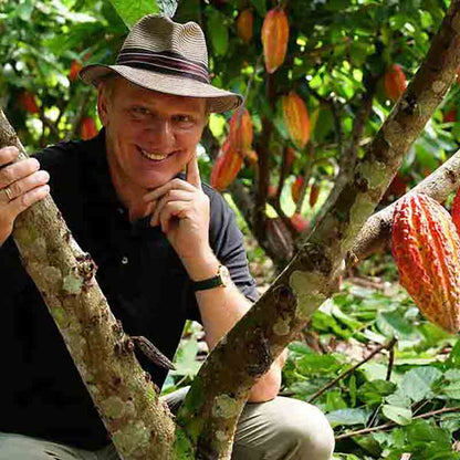 Mann im Garten mit Kakaofrüchten.