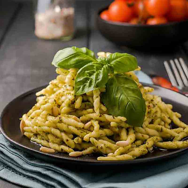 Trofie mit Pesto alla Genovese auf einem schwarzen Teller angerichtet.