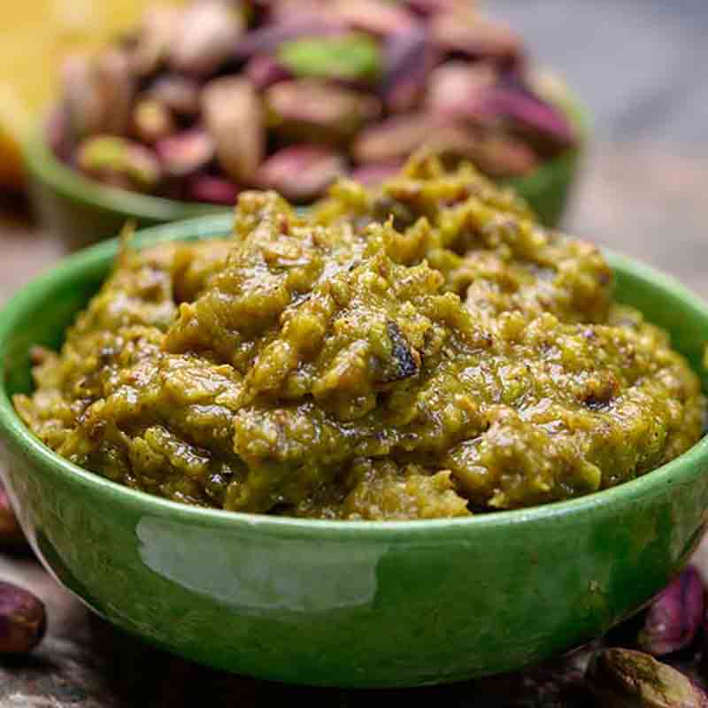 Grüne Schale mit Pistazienpesto, Hintergrund Pistazien.