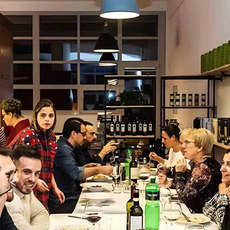 Menschen essen gemeinsam an einem Tisch mit Weinflaschen.