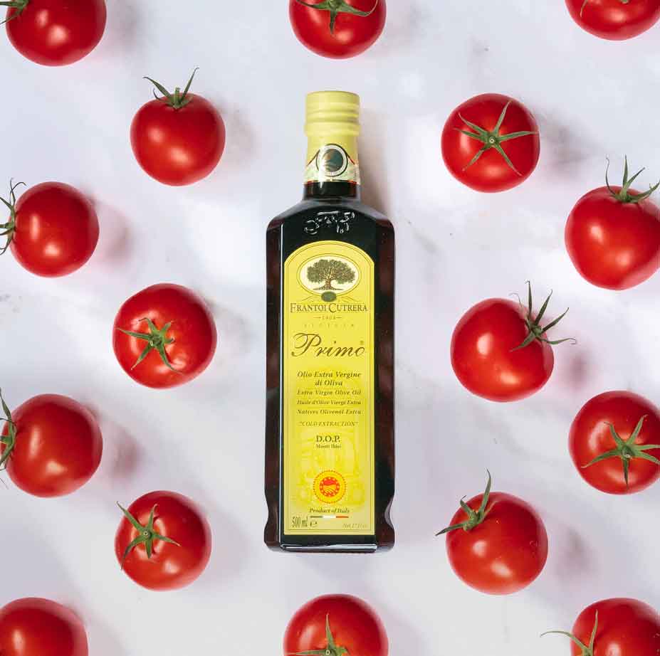 Flasche Primo Olivenöl umgeben von frischen Tomaten.