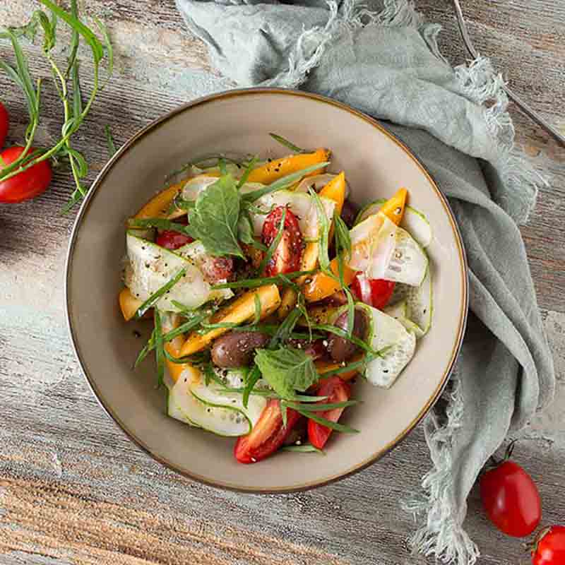 Salat mit Estragonessig, Tomaten, Gurken, Oliven, Kräutern, Tuch.