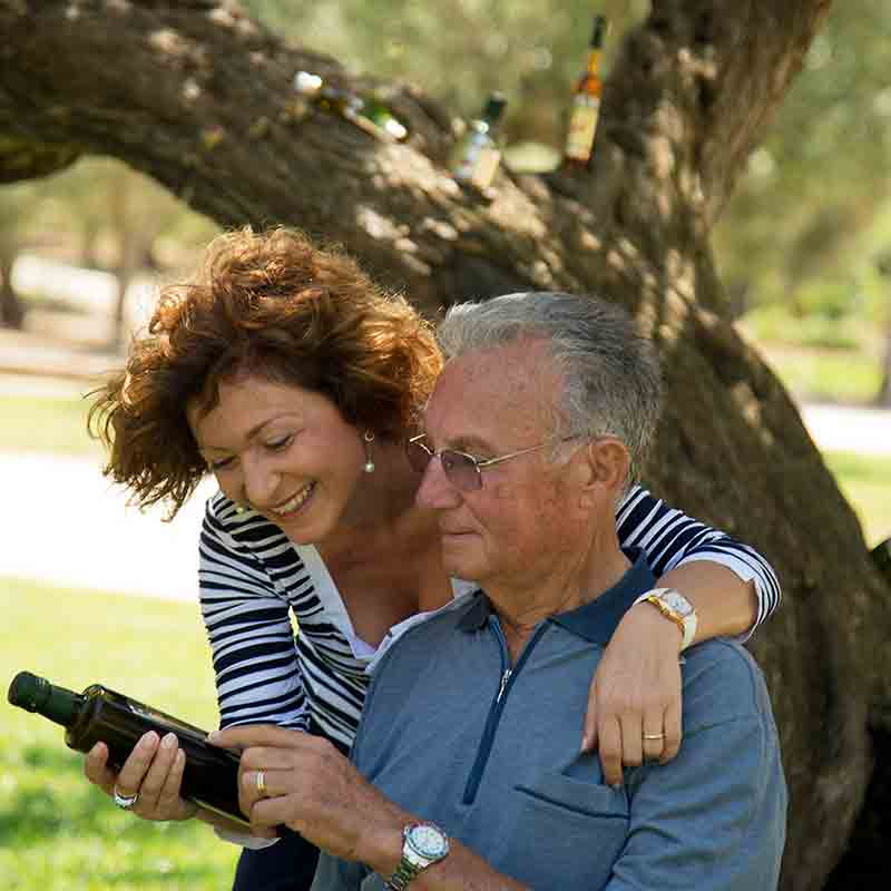 San Calogero schaut sich zusammen mit seiner Ehefrau eine Flasche seiner Olivenöle an.