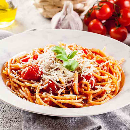 Spaghetti mit Tomaten, Basilikum und geriebenem Käse auf Teller.