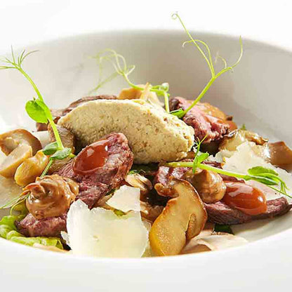 Feinkostgericht mit Steinpilzcreme, Fleisch, Pilzen und Parmesan.