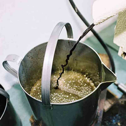 Kürbiskernöl fließt in Metallbehälter aus Presse.