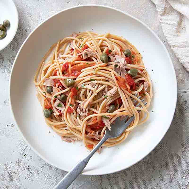 Pasta mit Tomatensauce, Kapern und Thunfisch auf Teller.
