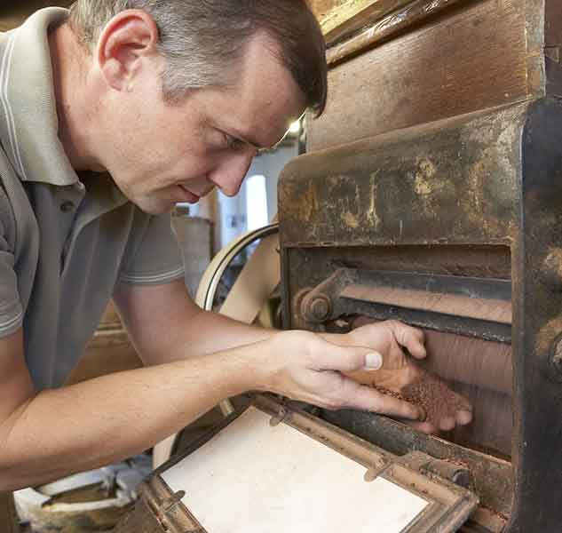 Mann arbeitet an Ölmühle.