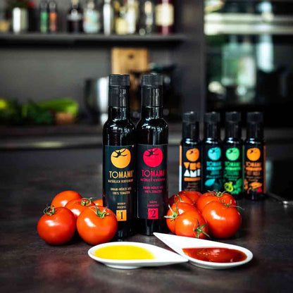 Tomami Flaschen, Tomaten, Olivenöl, Essig, Feinkost auf Tisch.