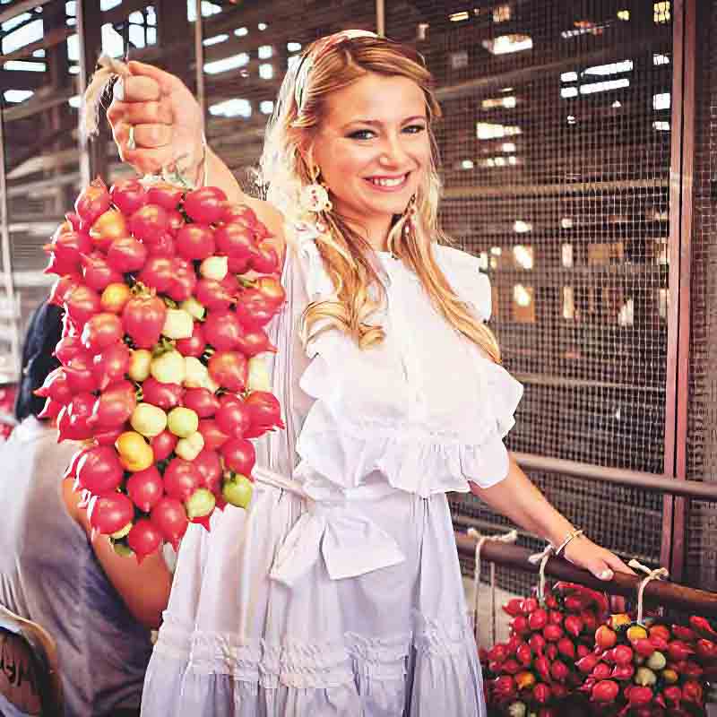 Frau hält Tomatenstrang hoch.