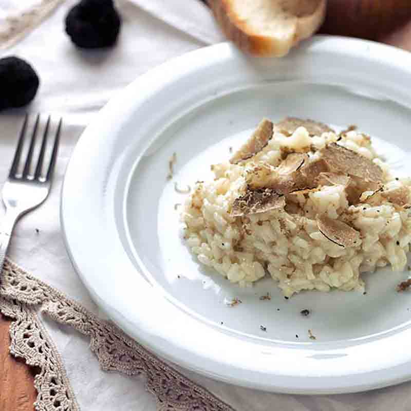 Trüffelrisotto auf Teller mit Gabel und Brot.