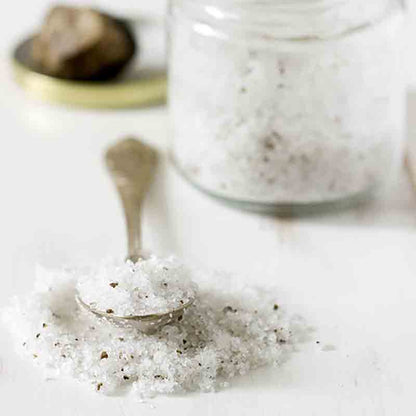 Trüffelsalz in Glas und Löffel auf weißem Hintergrund.