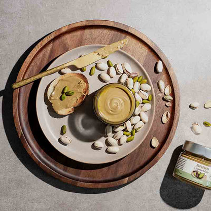 Pistaziencreme auf Teller mit Pistazien und Messer.