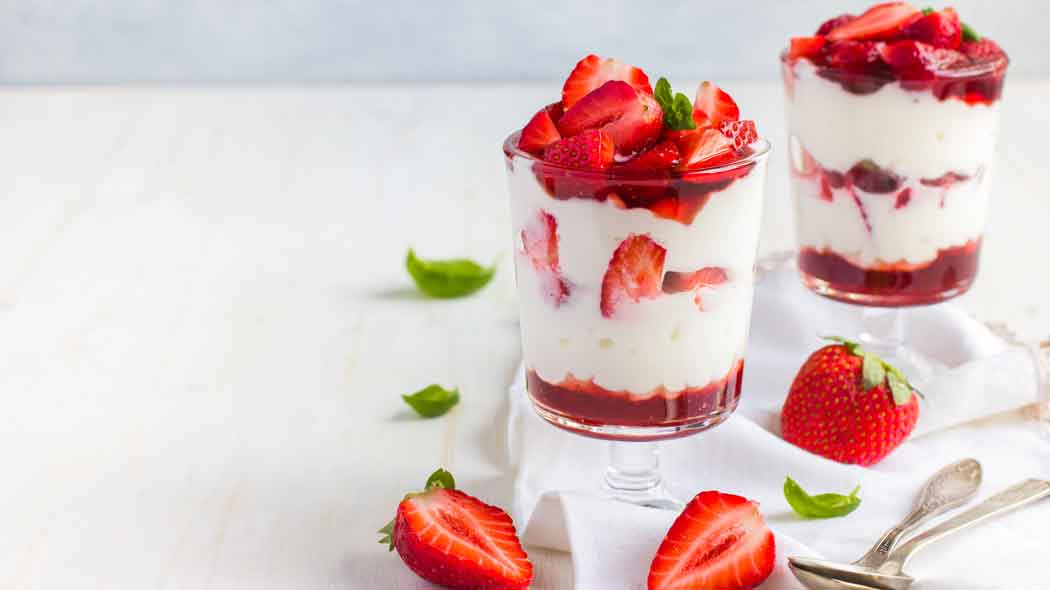 Dessert mit Erdbeeren und Sahne in Gläsern serviert.