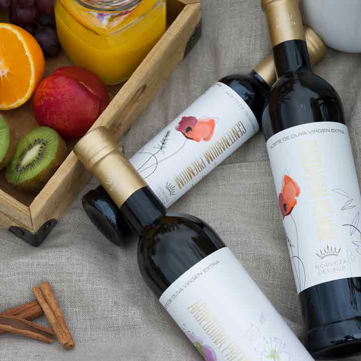 Olivenölflaschen von Nobleza del Sur mit Obstarrangement.
