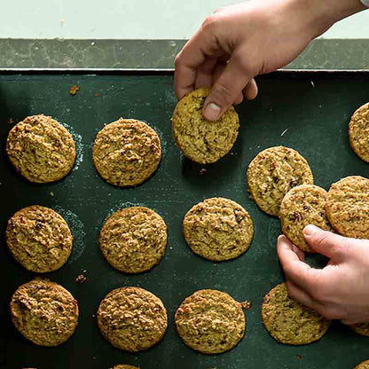 Hände arrangieren Kekse auf Blech.