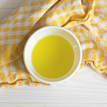 Schale mit Basilikumöl auf gelbem Tuch.