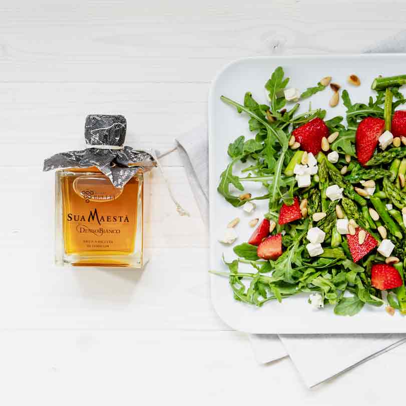 Essigflasche Sua Maesta neben Salat mit Erdbeeren.