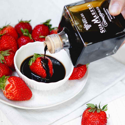 Essig von Bellei über Erdbeeren auf Teller gegossen.