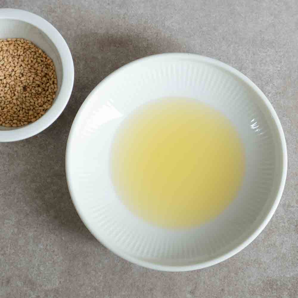 Schale mit Sesamöl und Schale mit Sesamsamen.