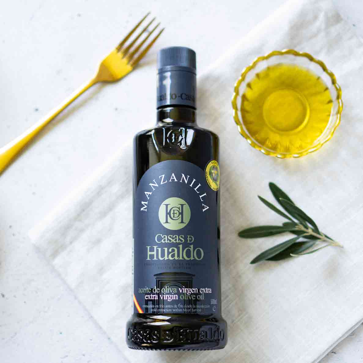 Flasche Casas de Hualdo Olivenöl mit Olivenzweig und Schale.