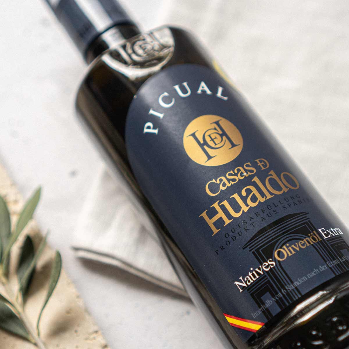 Flasche Casas de Hualdo Picual Olivenöl auf Tisch.
