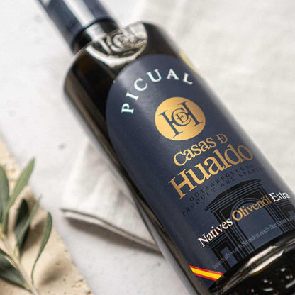 Flasche Casas de Hualdo Picual Olivenöl auf Tisch.