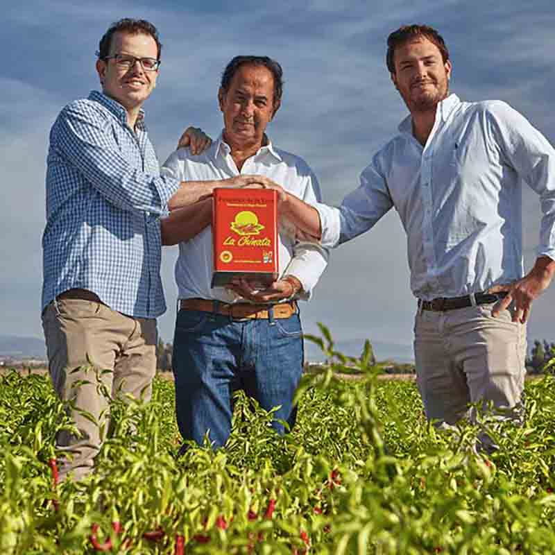 Eigentümer der Manufaktur halten eine große Dose Pimenton de la Vera zu dritt in den Händen.