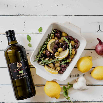 Centonze Olivenöl, Oliven, Zitronen, Rosmarin, Knoblauch auf Holztisch.