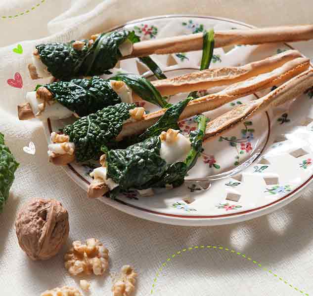 Grissini mit Käse, Walnüssen und Kohl auf Teller.