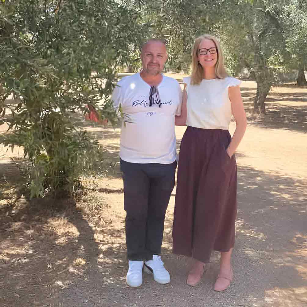 Andrea Jendral steht nah neben einem Ölmüller aus Apulien in seinen Olivenhainen.