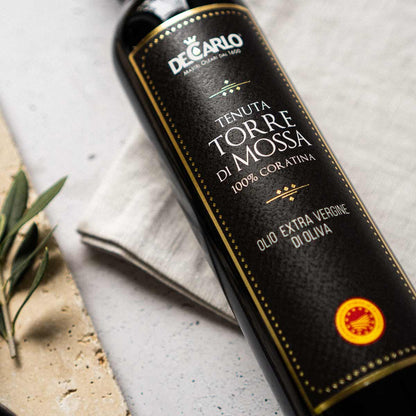 De Carlo Olivenölflasche mit Etikett auf hellem Hintergrund.