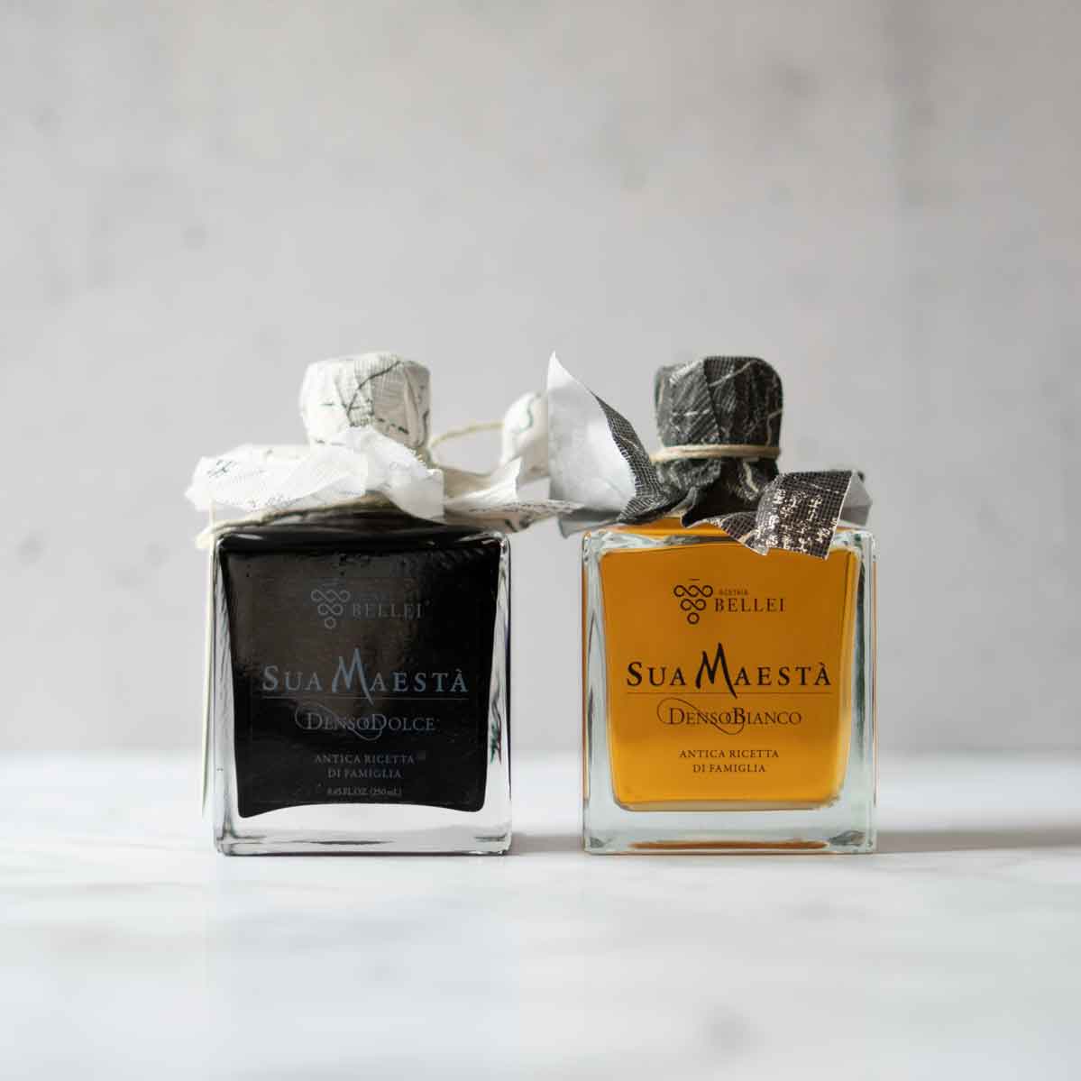 Zwei Sua Maestà Essigflaschen auf hellem Hintergrund.