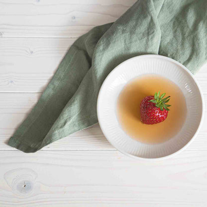 Schale mit Erdbeere in Balsamico auf Holztisch.