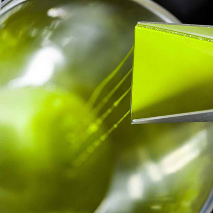 Frisch gepresstes Olivenöl tropft in einen Behälter.