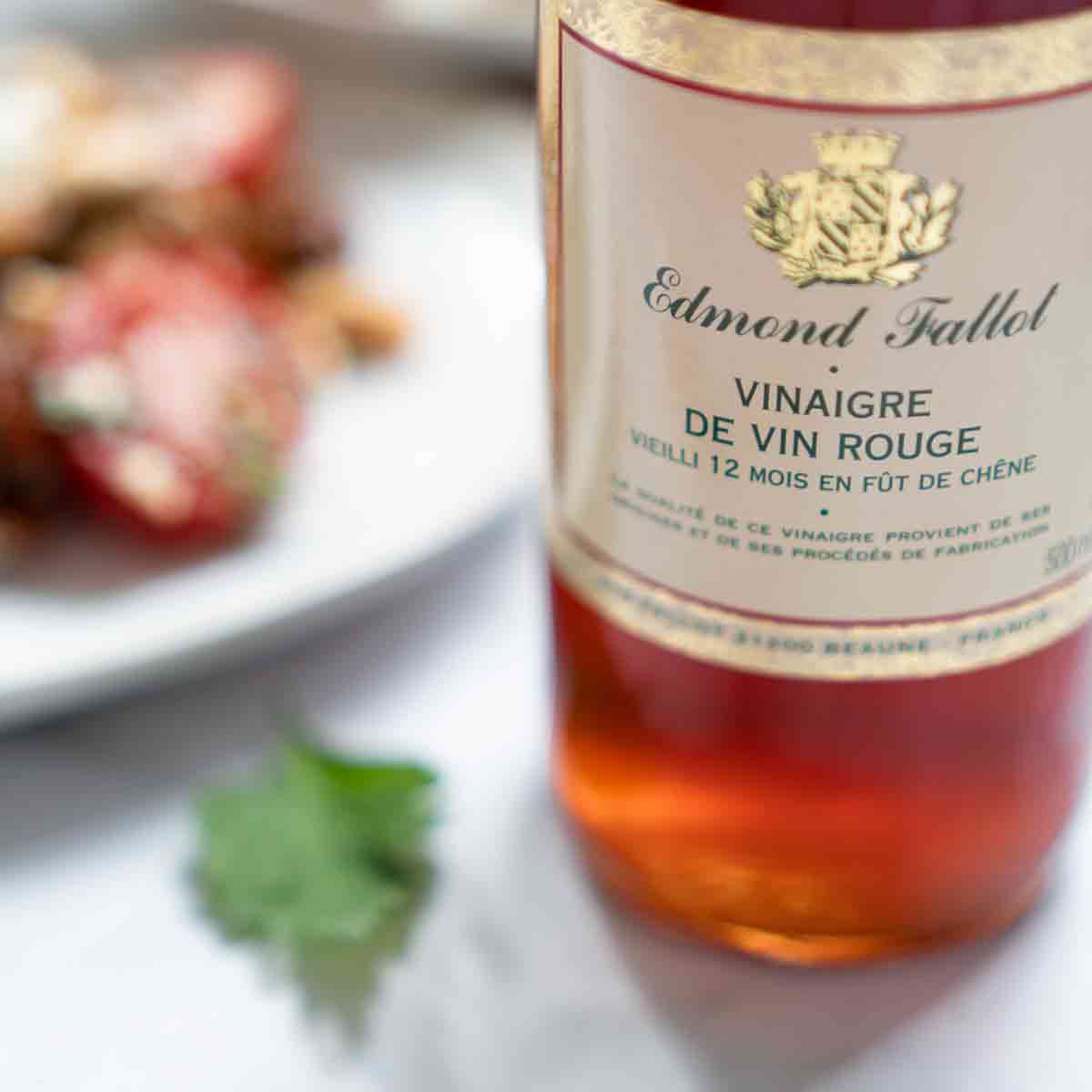 Edmond Fallot Rotweinessig Flasche neben Teller mit Speisen.