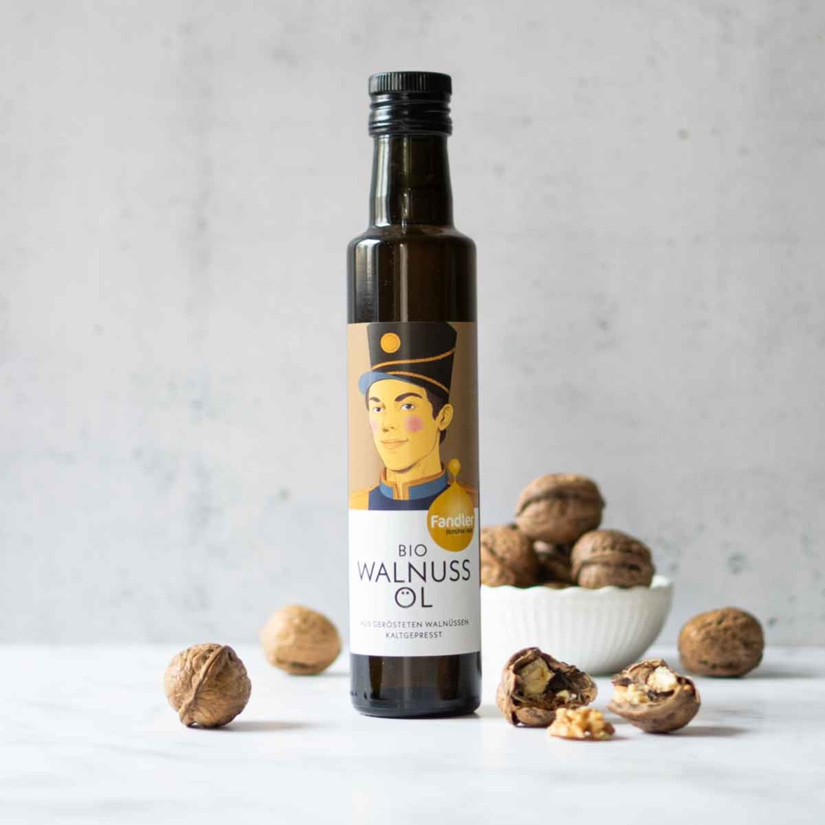 Fandler Walnussöl-Flasche mit Walnüssen auf hellem Hintergrund.