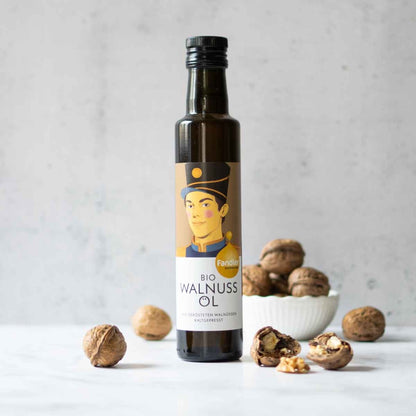 Fandler Walnussöl-Flasche mit Walnüssen auf hellem Hintergrund.