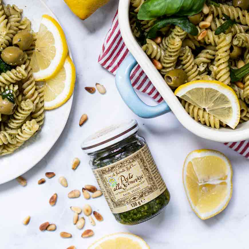 Pesto-Glas mit Pasta, Zitronenscheiben und Pinienkernen dekoriert.